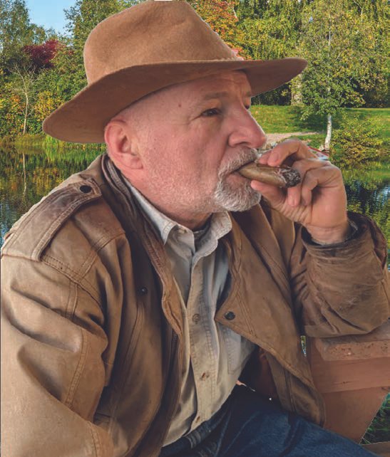 Chef Philippe Parola wearing a brown hat and smoking a cigar — photograph from the book’s back cover